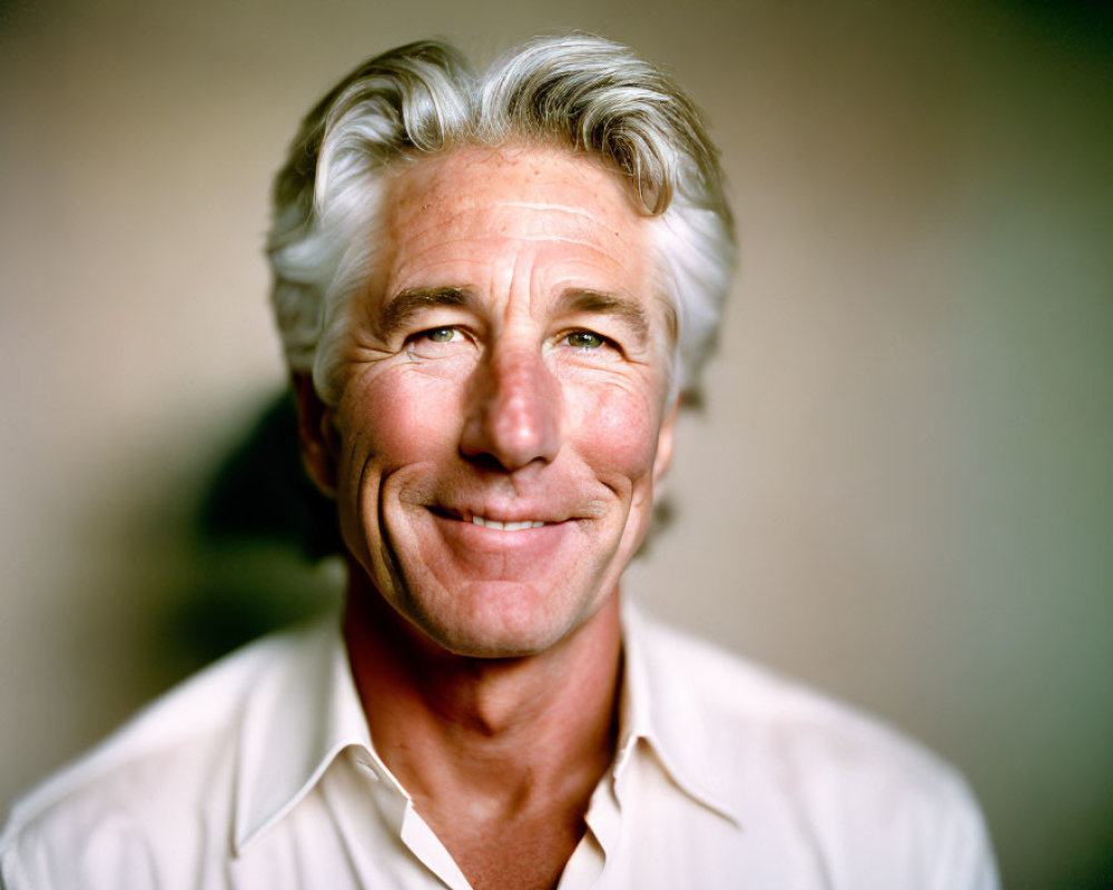 Smiling man with gray hair in white shirt portrait