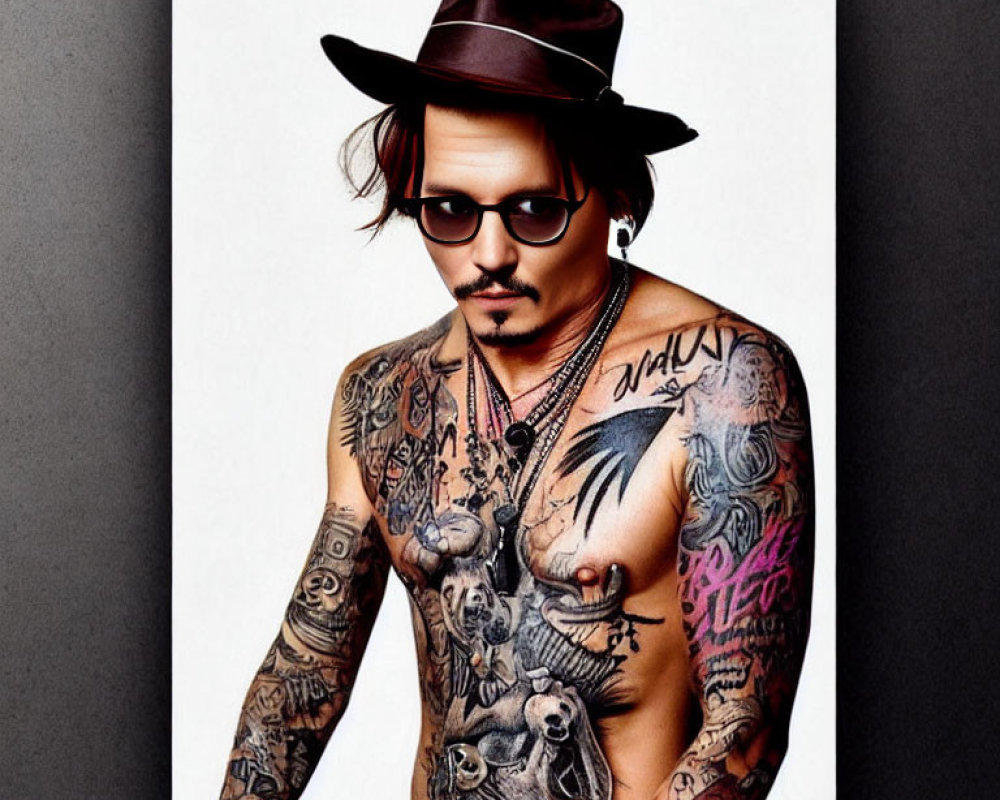 Person with Goatee, Hat, Sunglasses, and Tattoos on Chest and Arms poses on White