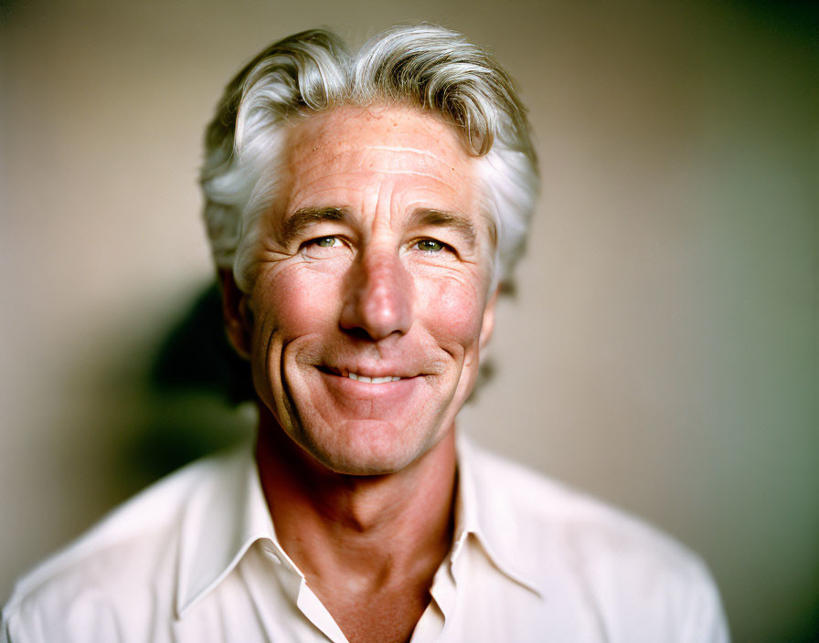 Smiling man with gray hair in white shirt portrait