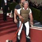 Two men with dog in tandem baby carrier on red-carpeted stairs