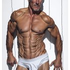 Grey-Haired Muscular Man in White Briefs on Wooden Background