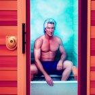 Silver-Haired Man Contemplating in Sauna with Wooden Benches and Red Door