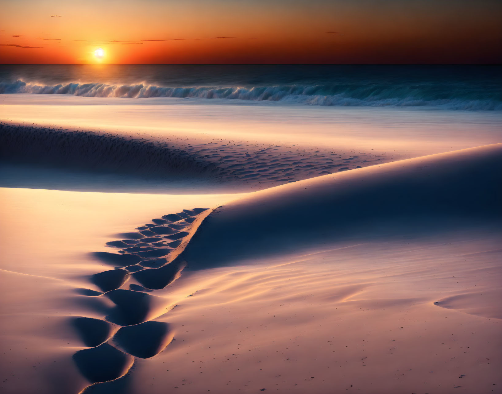 Tranquil beach scene: sunset, gentle waves, footprints in sand