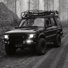 Black off-road vehicle with roof-top tent in forested area for outdoor adventure.