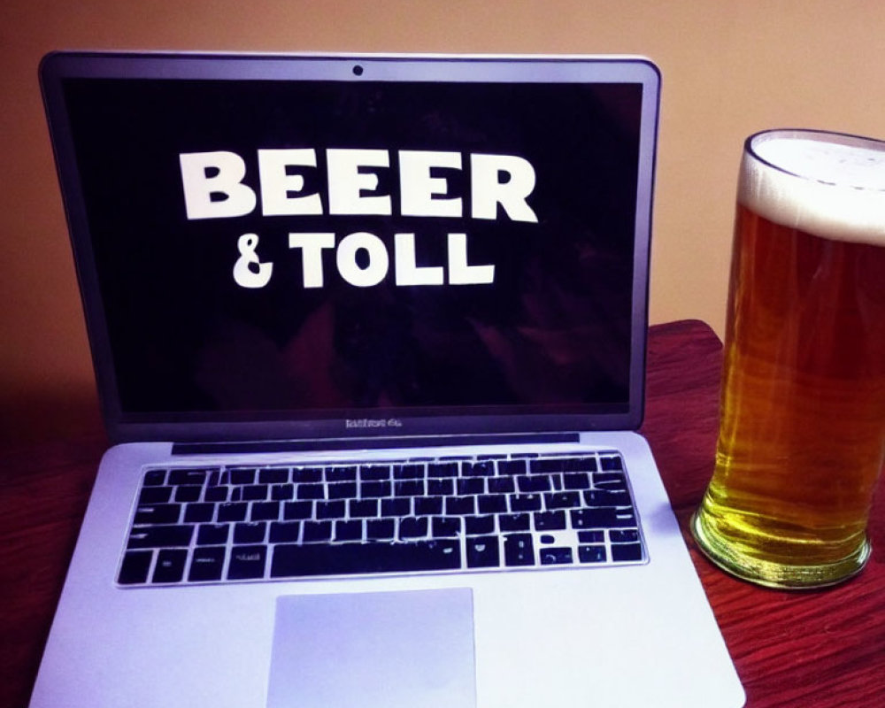 Laptop screen showing "BEER & TOLL" next to beer glass on table