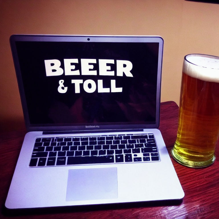 Laptop screen showing "BEER & TOLL" next to beer glass on table