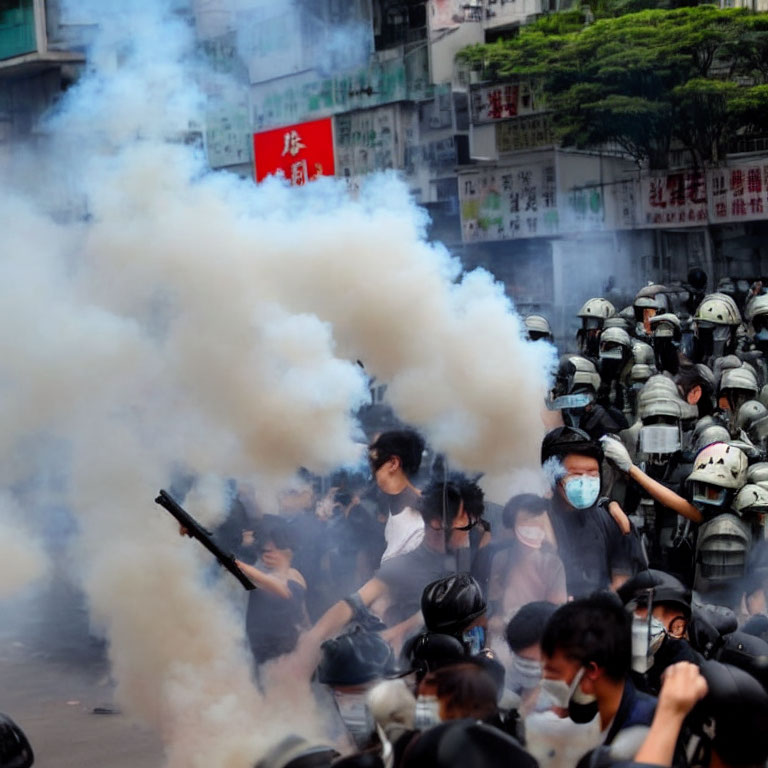 Crowd in Masks and Riot Gear Amid Tear Gas in Cityscape