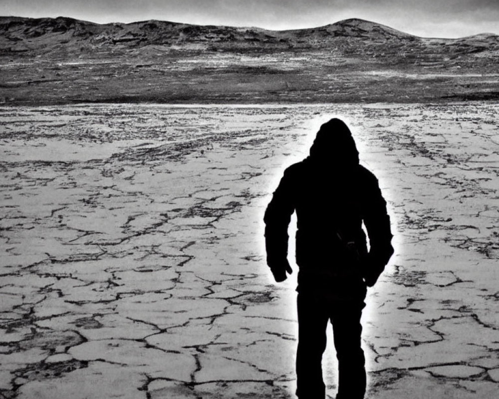 Barren landscape with silhouetted figure and dramatic sky