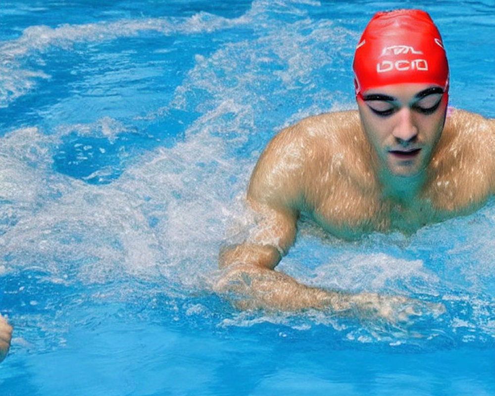 Swimmer in Red Cap Mid-Stroke in Clear Blue Pool