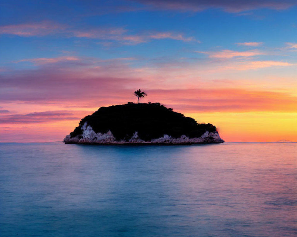 Tranquil sunset scene: small island, lone palm tree, pink and blue sky hues.