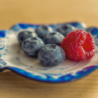 Ripe Blueberries and Raspberries on Blue Plate