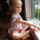 Blonde woman in vintage lace dress gazes out window in textured setting