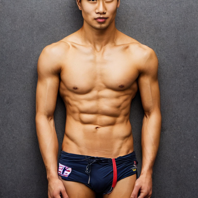 Muscular man in UK flag swim briefs on grey backdrop