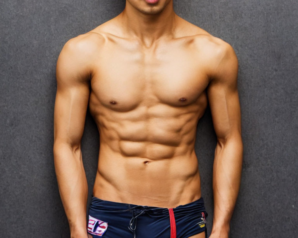 Muscular man in UK flag swim briefs on grey backdrop