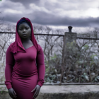 Woman in pink dress against stormy sky with blurred figure