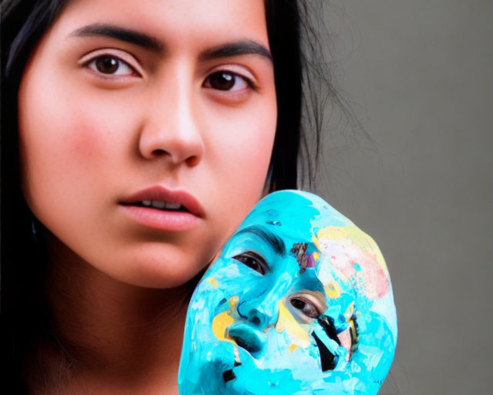 Woman Holding Colorful Painted Mask on Stick with Neutral Background