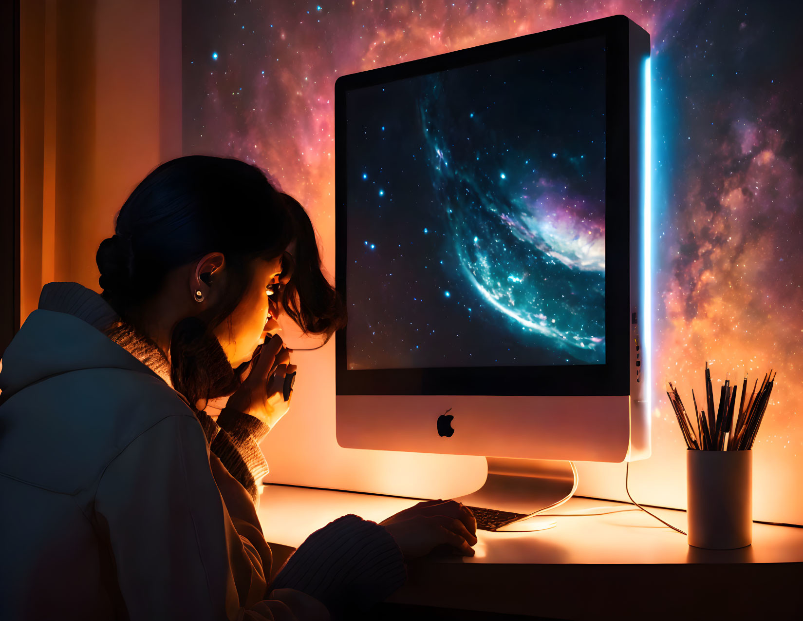 Person studying in dimly lit room with cosmic galaxy theme on computer screen