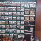 Assorted spices in jars on wooden shelves with fruits and greenery