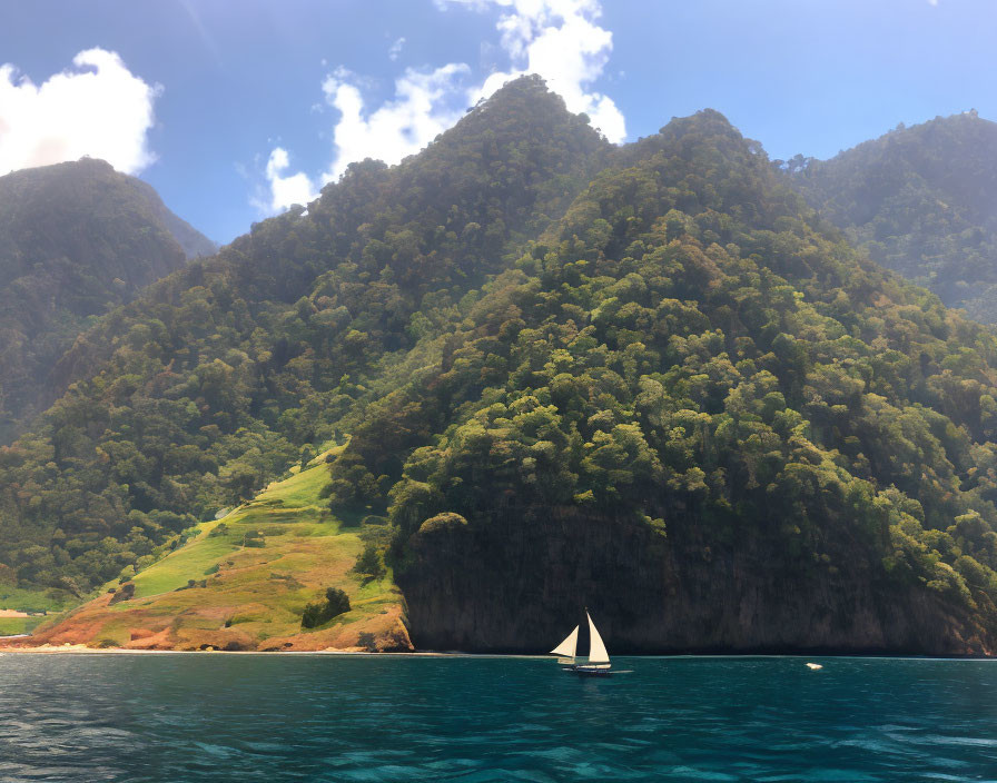 Sailboat on Blue Water Near Green Mountainous Coast