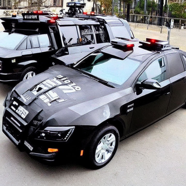 Black and white police cars with flashing lights parked outdoors