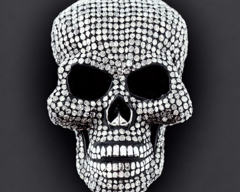 Skull-shaped object with shiny studs on dark background