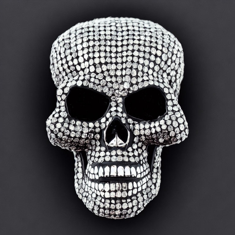 Skull-shaped object with shiny studs on dark background