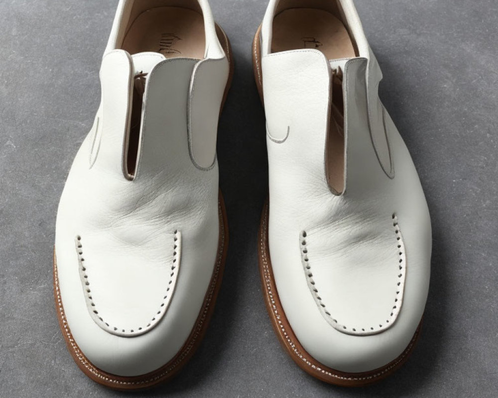 White Slip-On Dress Shoes with Brogue Detailing on Gray Background