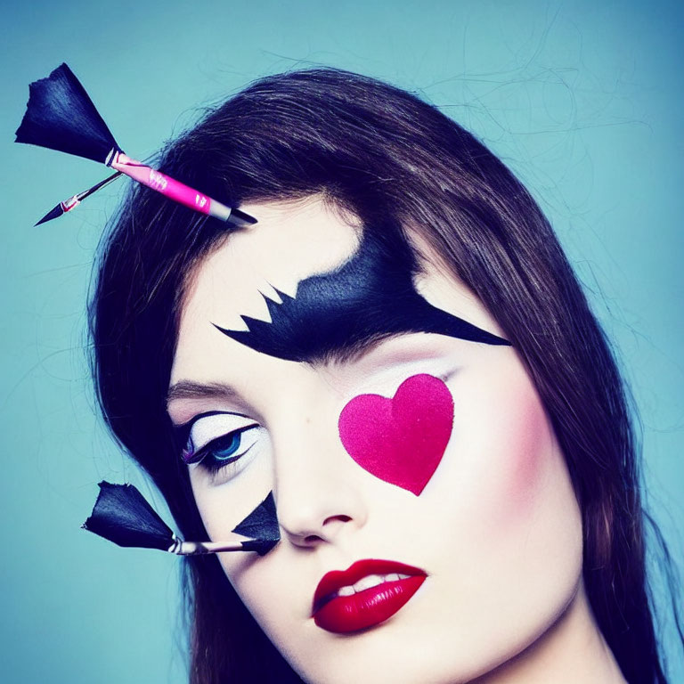 Woman with dramatic makeup: black eye mask, red lips, heart on cheek, pencil arrow.