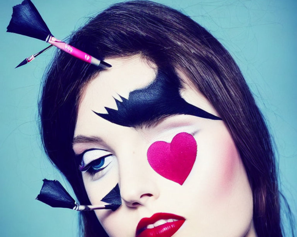 Woman with dramatic makeup: black eye mask, red lips, heart on cheek, pencil arrow.