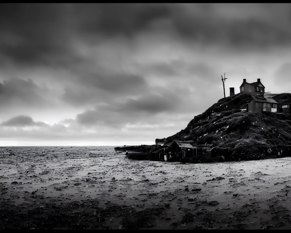 Monochrome image: desolate house on rocky outcrop by the sea under dramatic sky