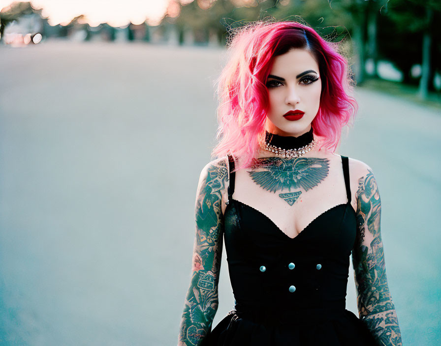 Confident woman with pink hair and tattoos in black dress and choker