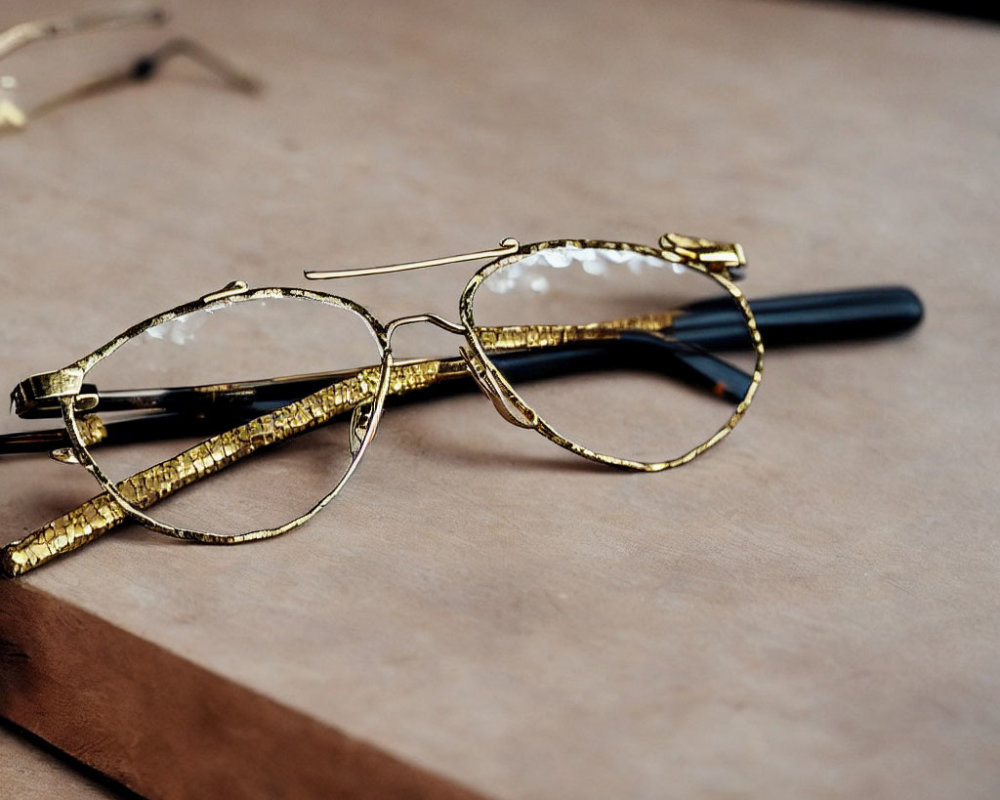 Gold-rimmed eyeglasses on book with textured surface