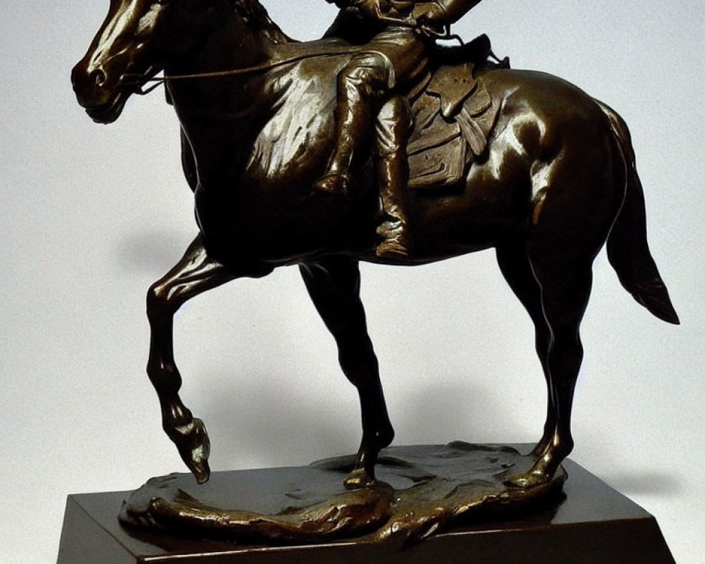 Bronze statue of rider on horse mid-trot on rectangular base