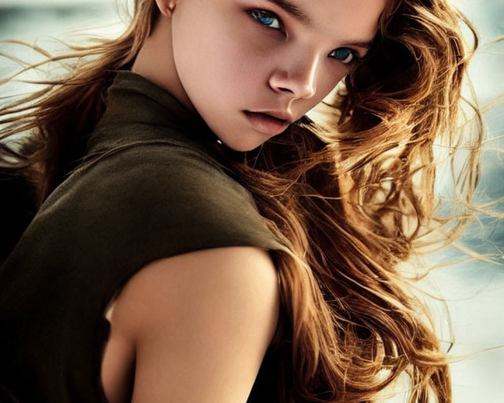 Portrait of person with wavy brown hair and blue eyes in khaki top