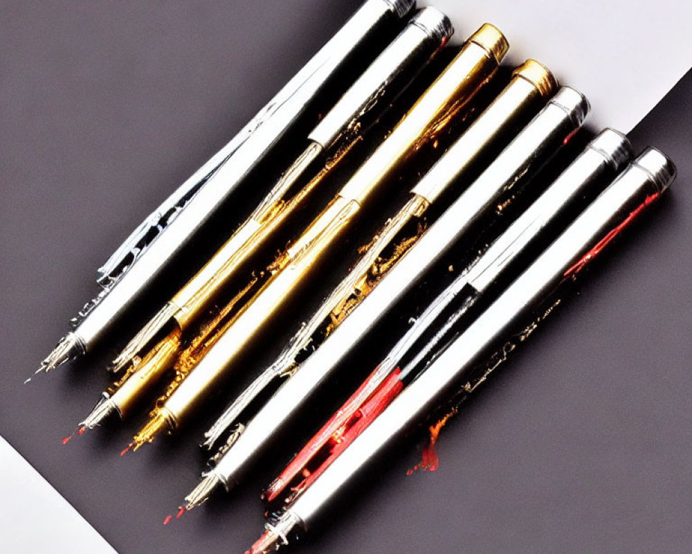 Six pens with gold and silver accents, showcasing nibs and ink reservoirs in various colors