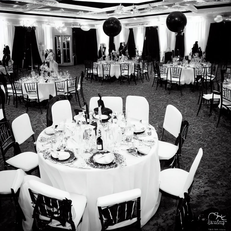 Monochrome photo of elegant dining hall with set tables and black balloons