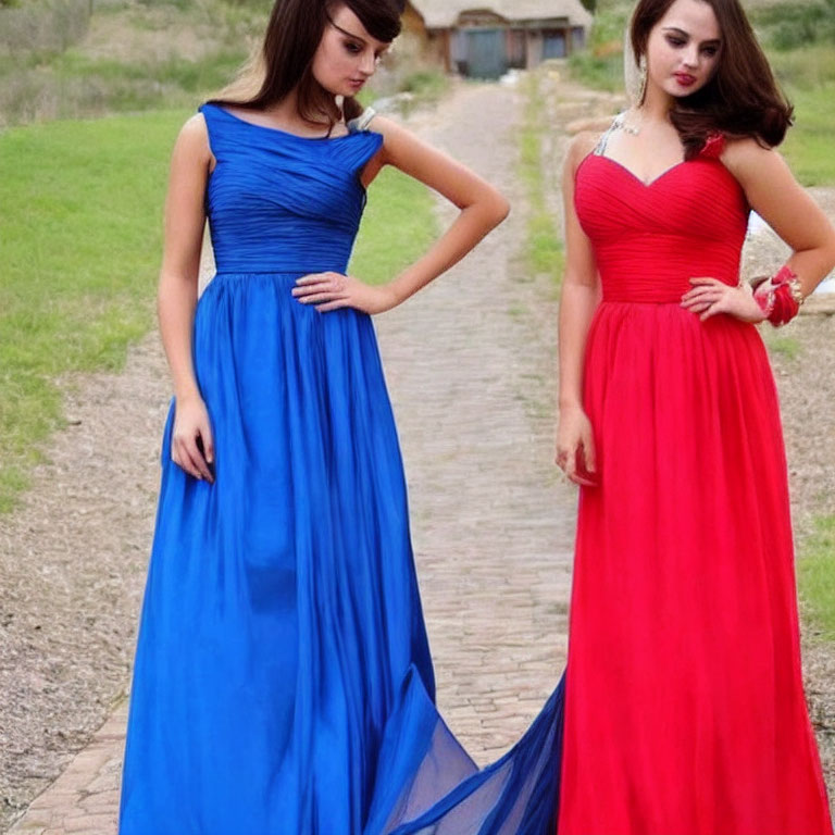 Two women in elegant blue and red gowns standing outdoors