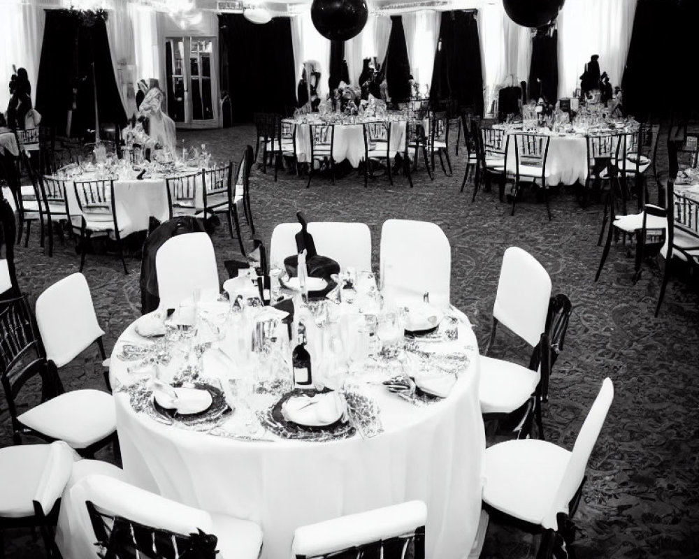 Monochrome photo of elegant dining hall with set tables and black balloons