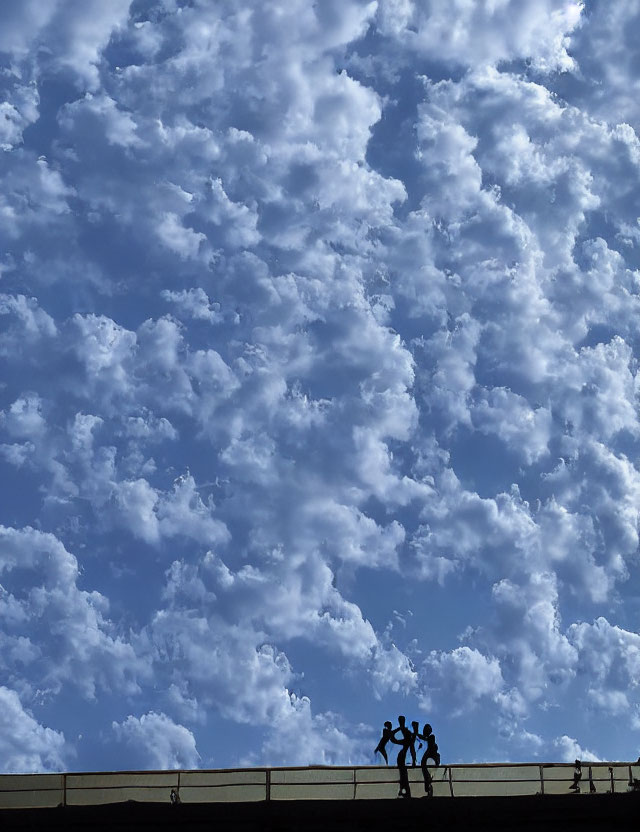 Three People Walking Silhouettes on Bridge Under Blue Sky