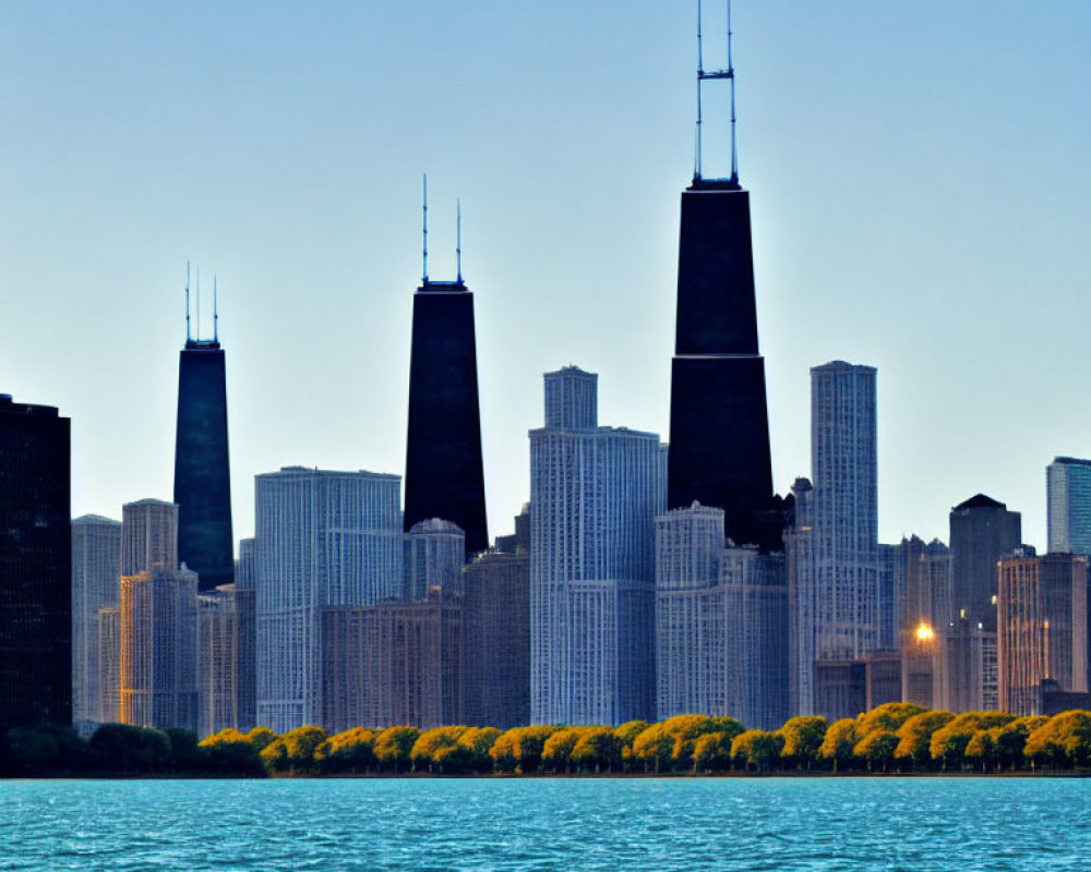 Urban skyline with tall skyscrapers near water under clear blue dusk sky