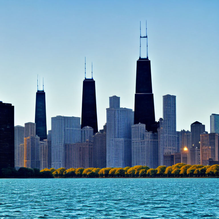 Urban skyline with tall skyscrapers near water under clear blue dusk sky