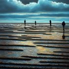 Three people walking on textured tidal flats under dramatic cloudy sky.