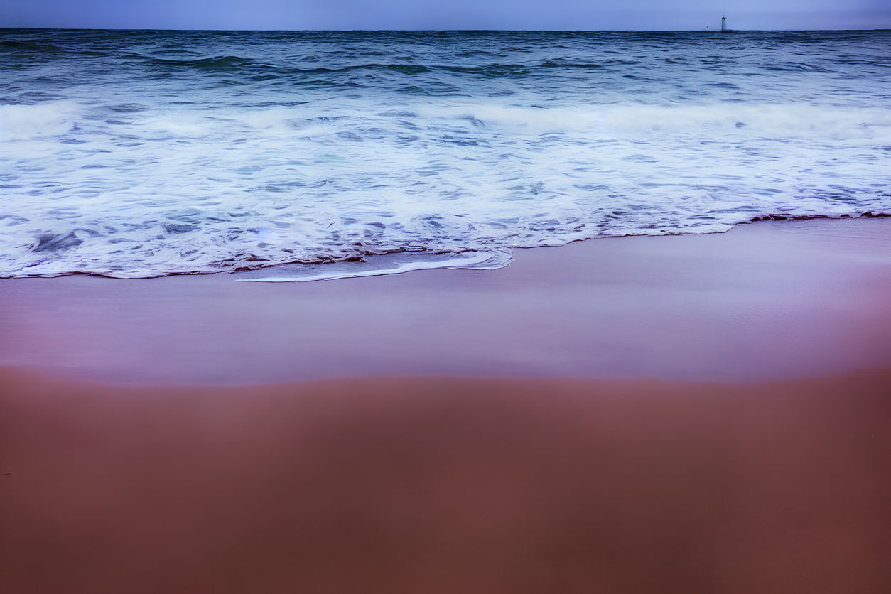 Seaside scene with ocean waves, sandy shore, and distant lighthouse