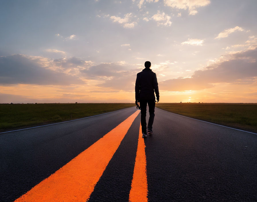 Person walking on center-lined road towards sunset in open sky