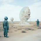 Astronauts viewing transparent spheres with tree silhouettes in grassy landscape