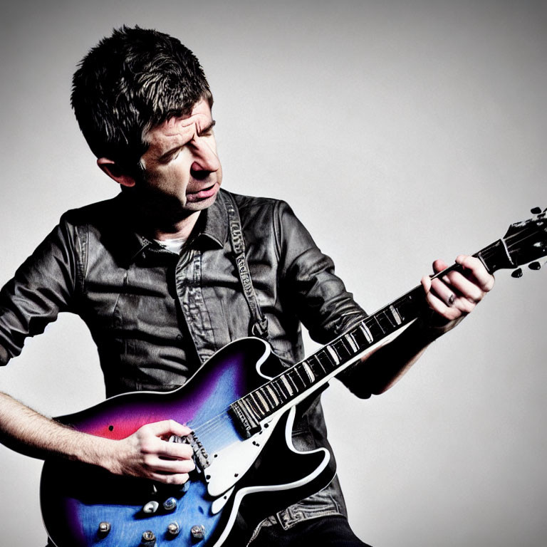 Man in dark shirt playing electric guitar on light grey background