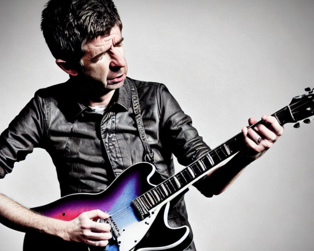 Man in dark shirt playing electric guitar on light grey background