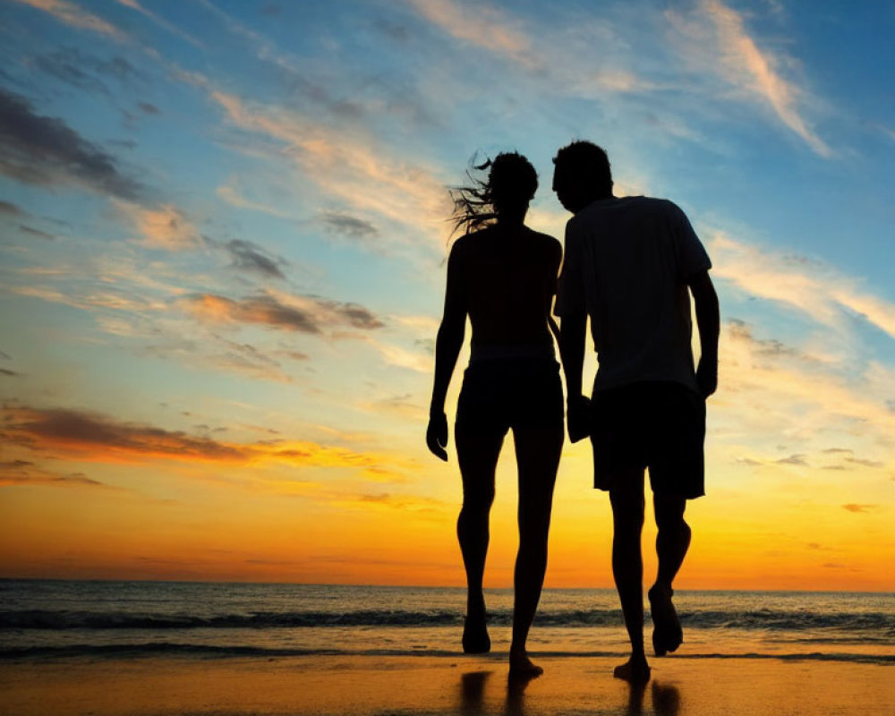 Romantic couple walking on beach at sunset with colorful sky and water reflection