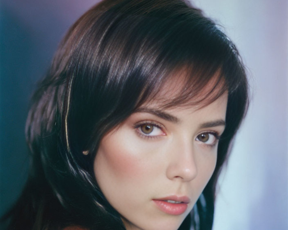 Portrait of woman with dark hair and fair skin against multicolored background in red garment