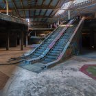 Abandoned escalator in dimly lit, derelict building